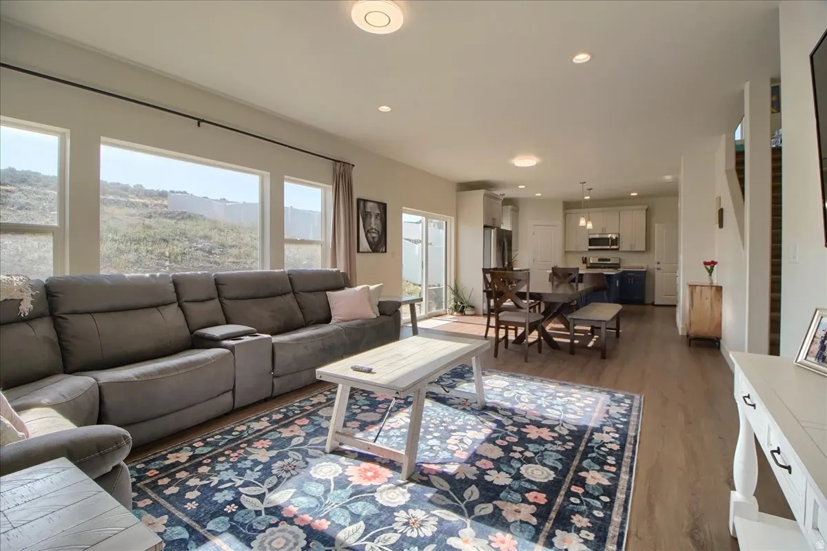 Open-concept living area featuring wood-finish flooring, a wall of windows, recessed lighting, and a sliding glass door