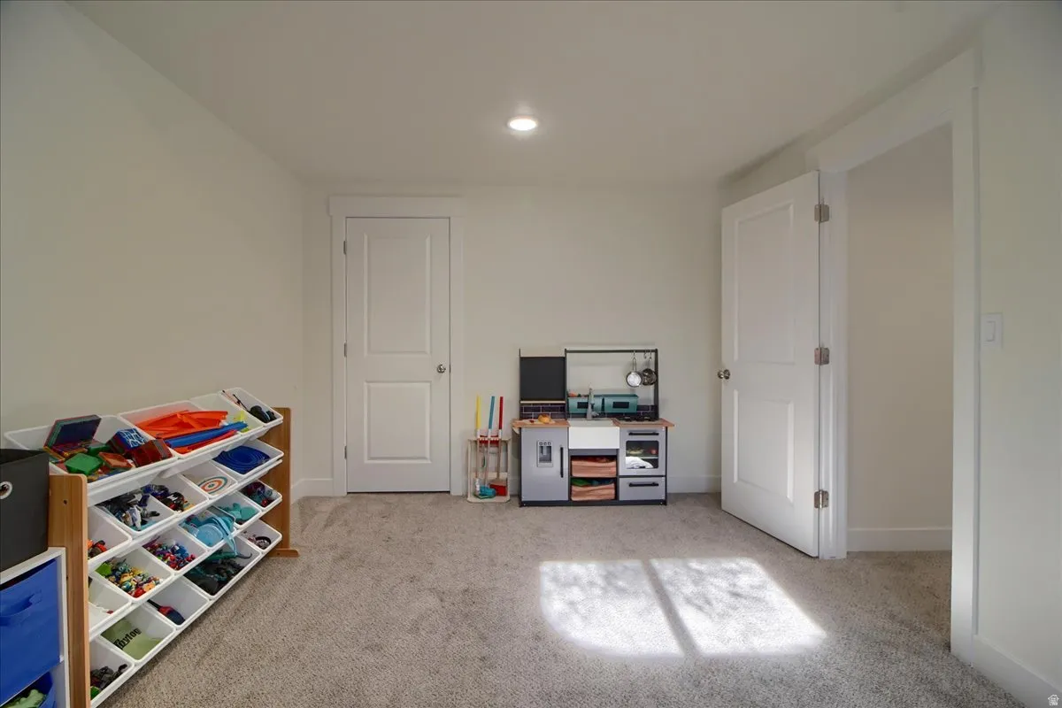 Spacious room featuring neutral carpeting, light-toned walls, and recessed lighting