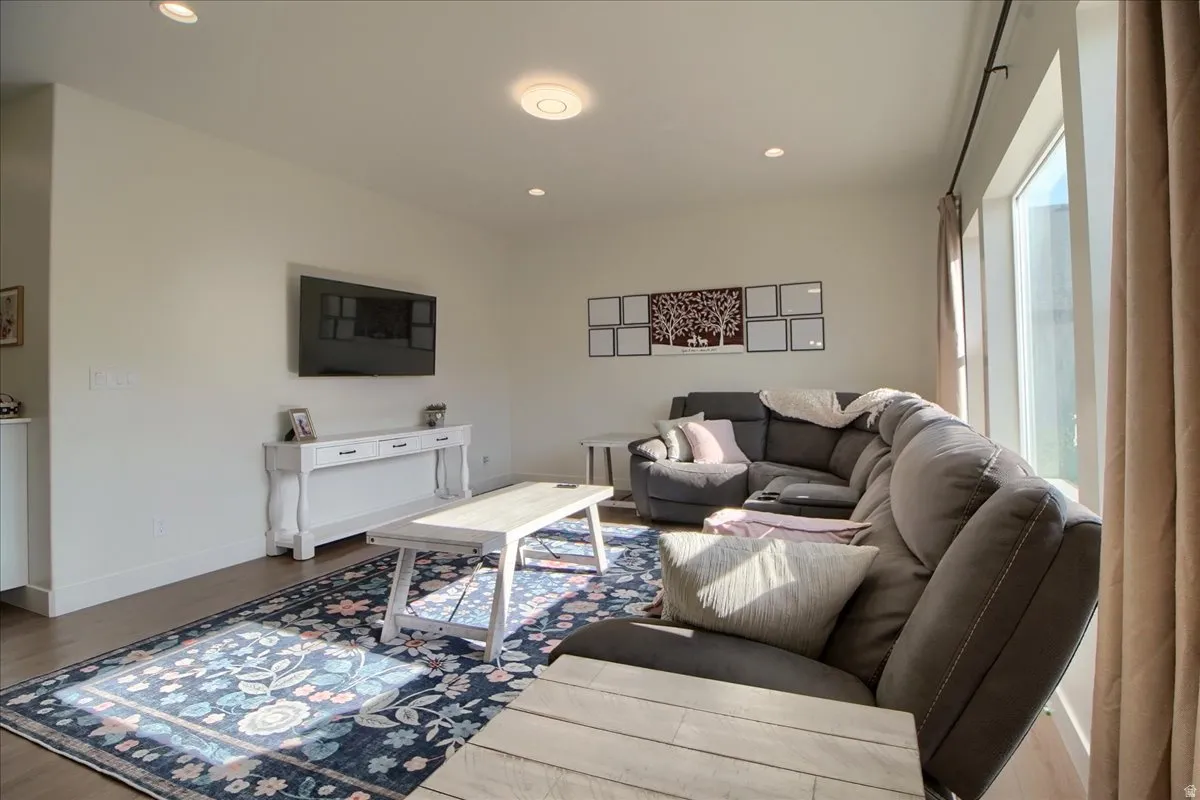 Open concept living space featuring light wall tones, recessed lighting, and wood-finish flooring