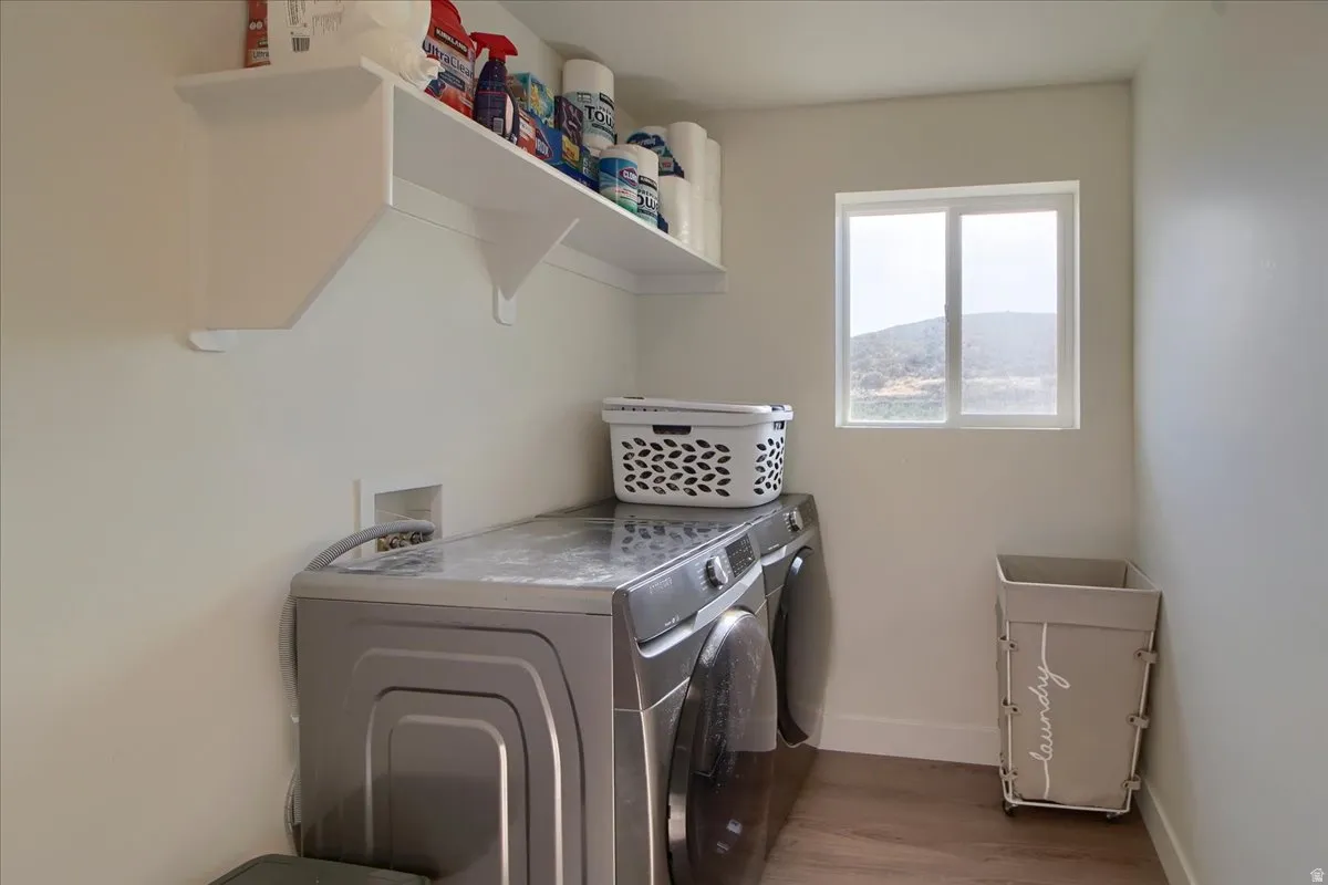 Dedicated laundry area featuring wood-finish flooring, white walls, and a window