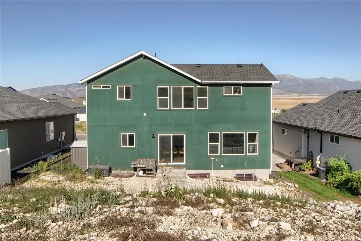 Two-story residence featuring a green stucco exterior and a dark shingle roof