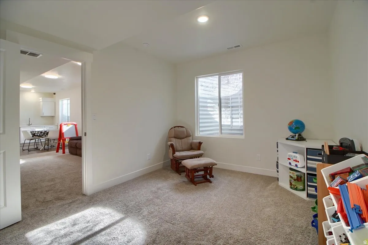 Carpeted room featuring a white window with horizontal blinds and recessed lighting