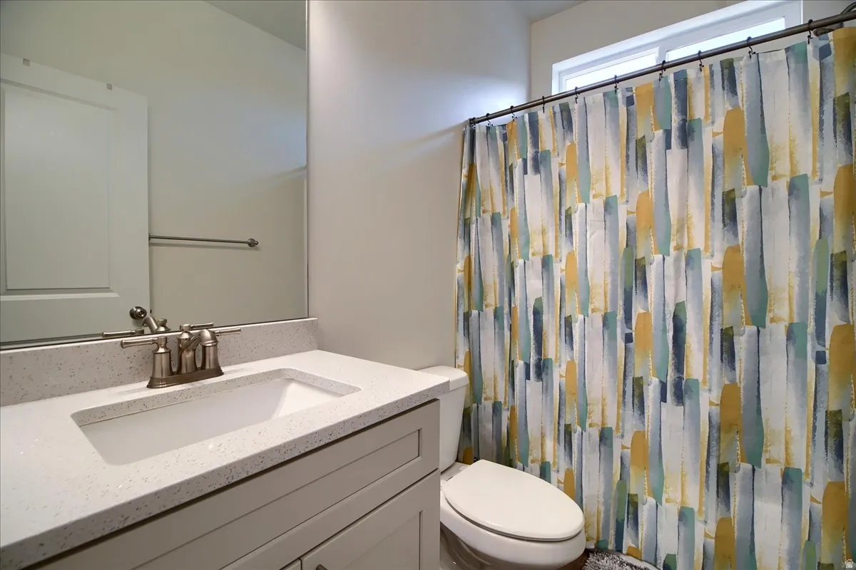 Contemporary bathroom featuring a white vanity with an integrated sink, a speckled countertop, and brushed nickel fixtures