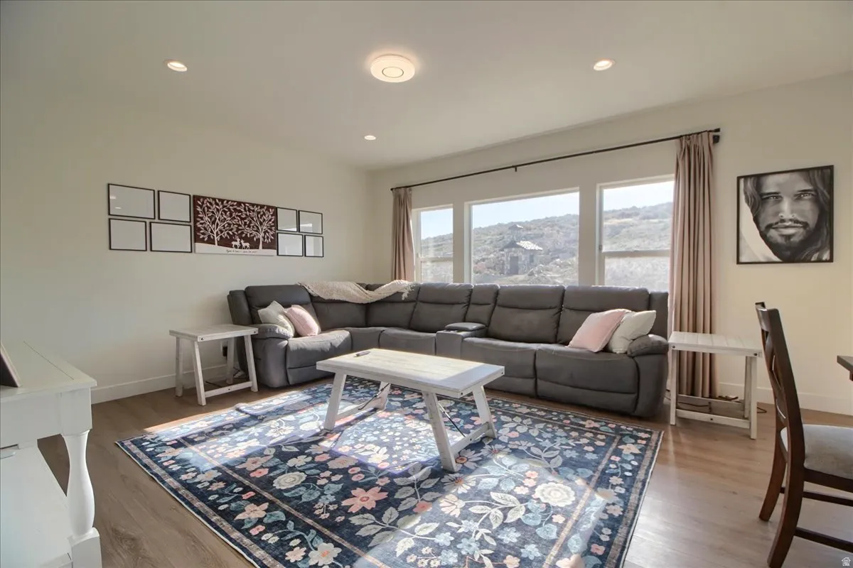 Living area featuring wood-finish flooring, recessed lighting, and a panoramic window wall with hillside scenery