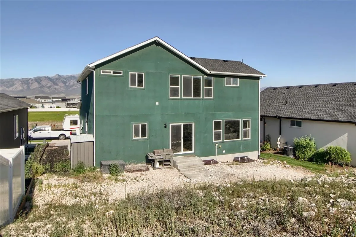 Two-story residence featuring a green exterior finish and a dark shingle roof