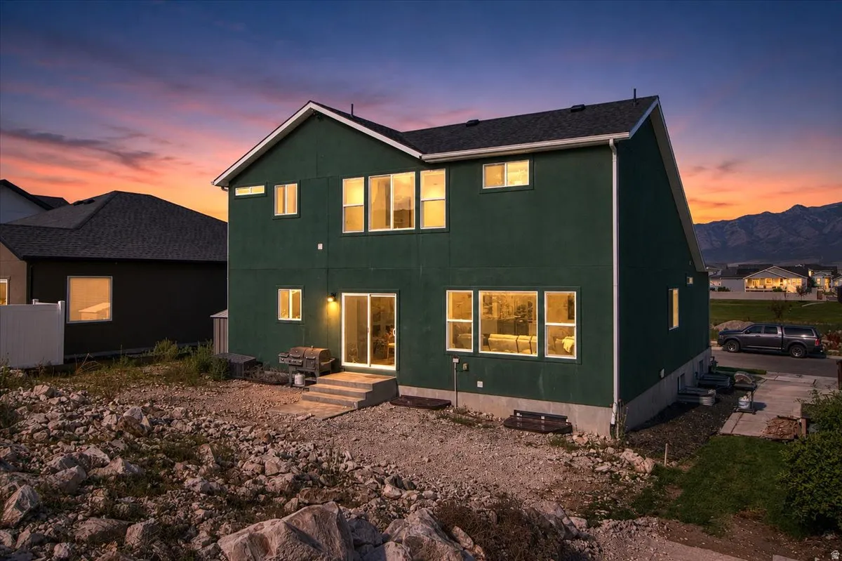Two-story residence featuring a dark green exterior, white-framed windows, and a black shingle roof