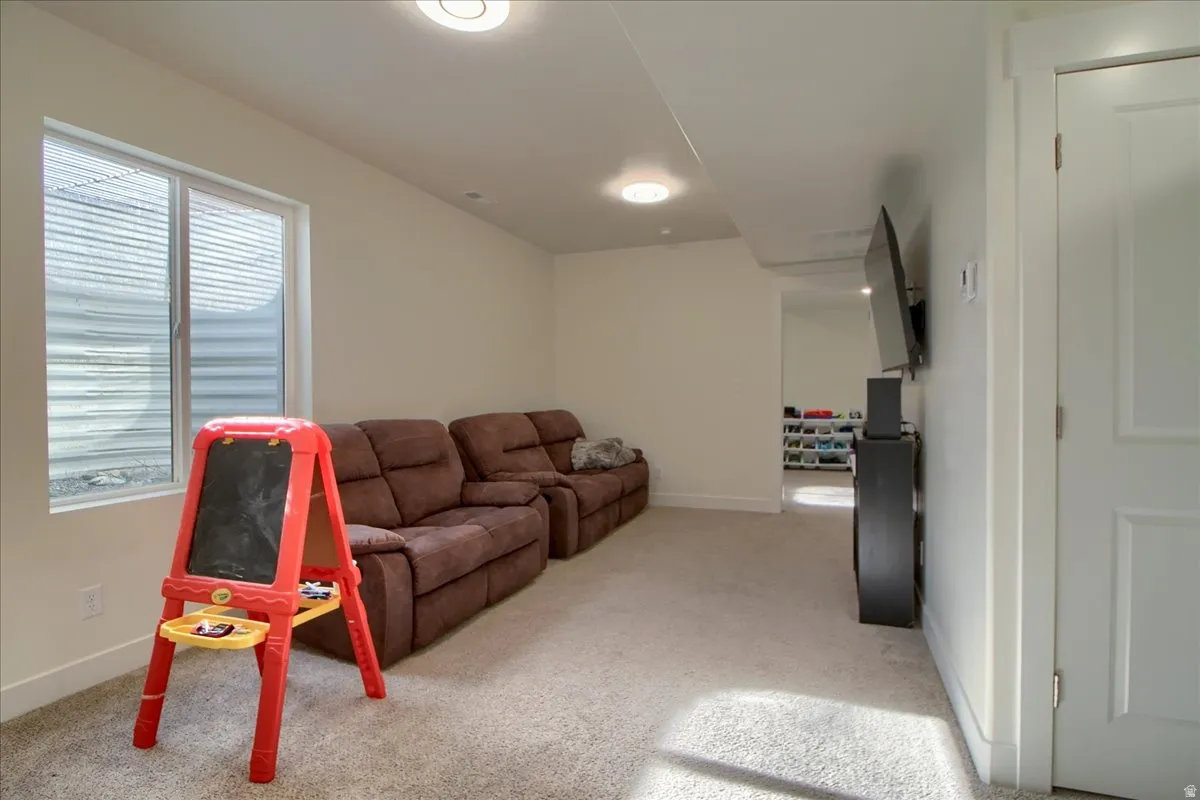 Carpeted lower-level living area featuring a large egress window, recessed lighting, and white baseboards