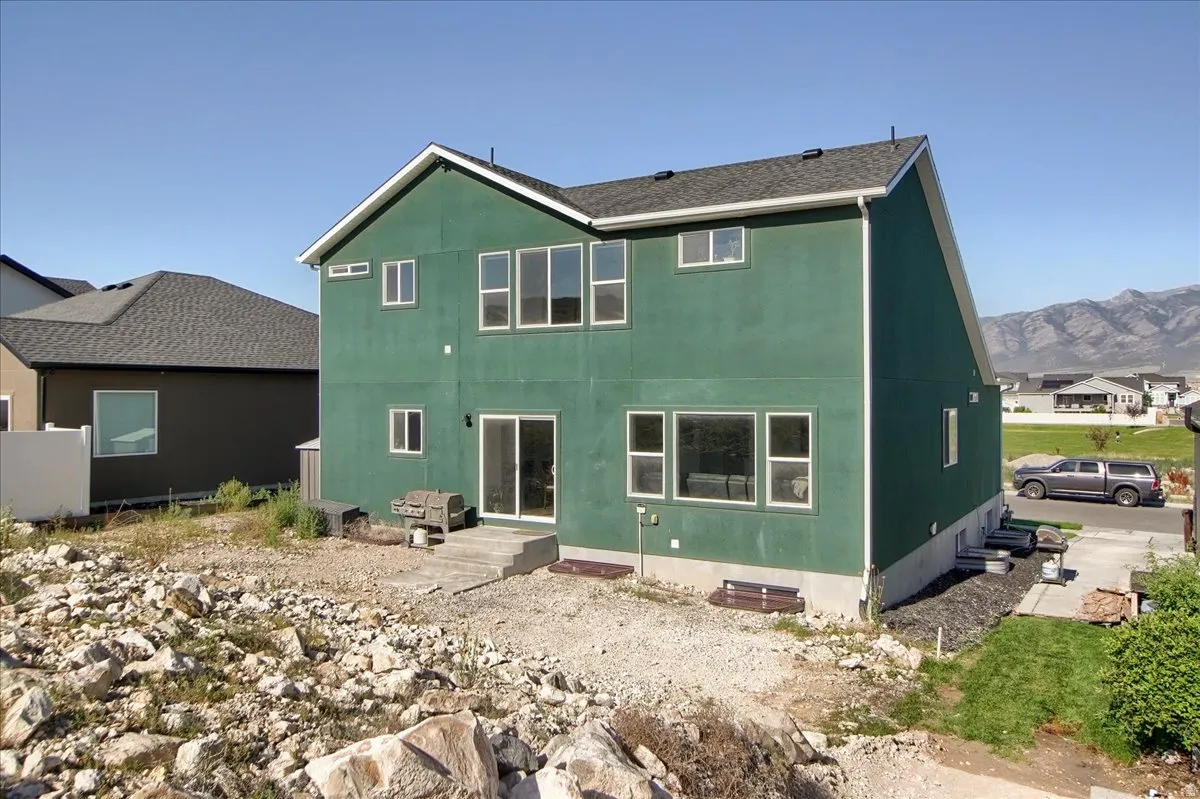 Two-story residence featuring a green exterior and a dark shingle roof