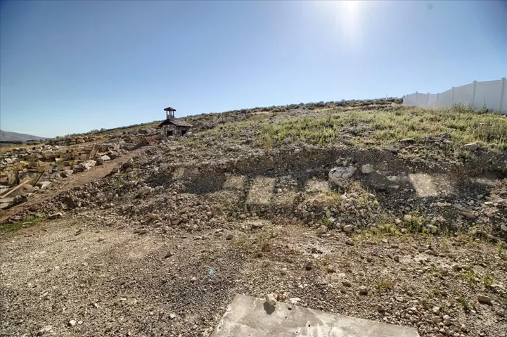 Sloping hillside lot with partial white fence along the perimeter