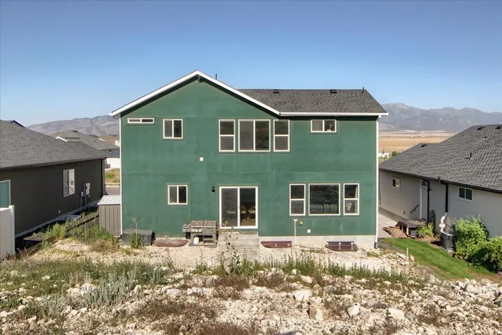 Two-story residence featuring a green stucco exterior and a dark shingle roof