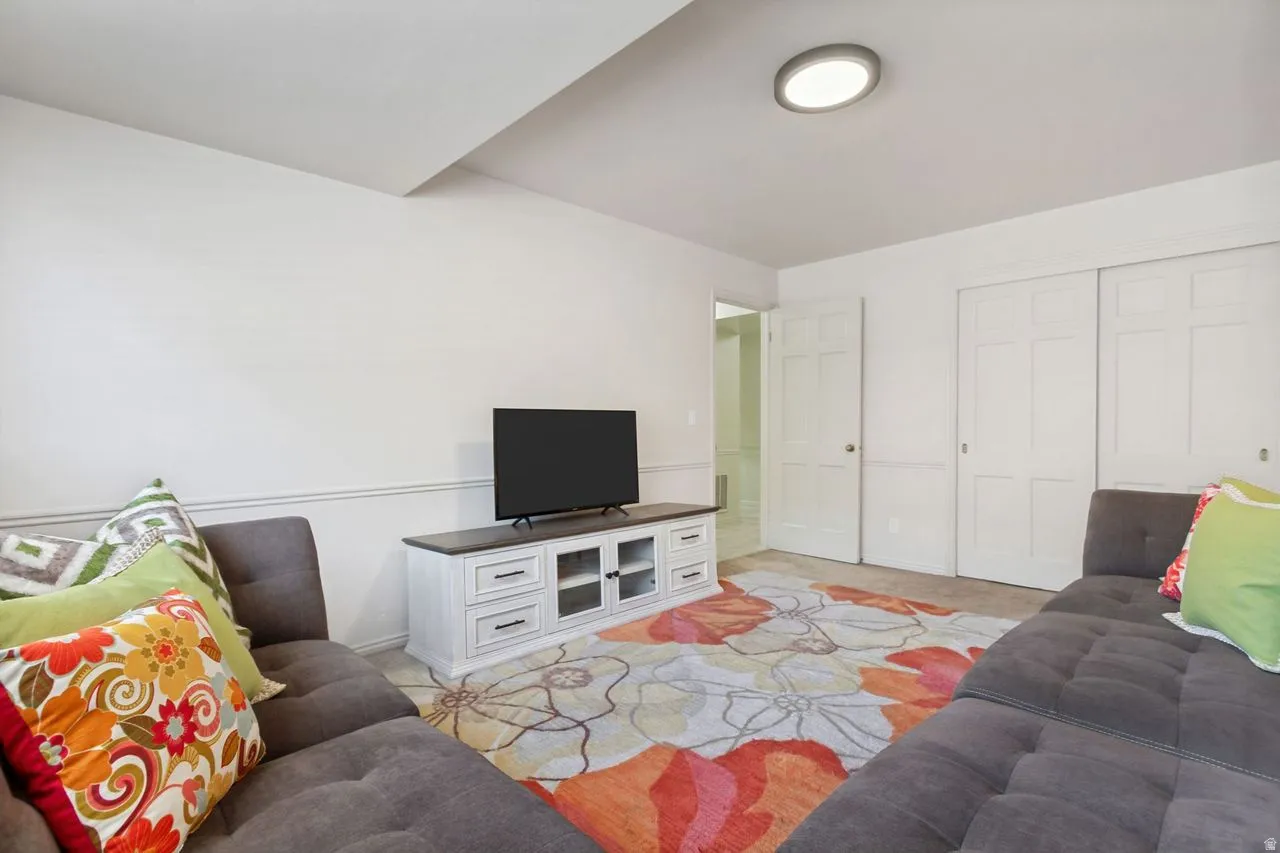 Carpeted interior space featuring white walls and a white ceiling with a flush-mount circular light fixture