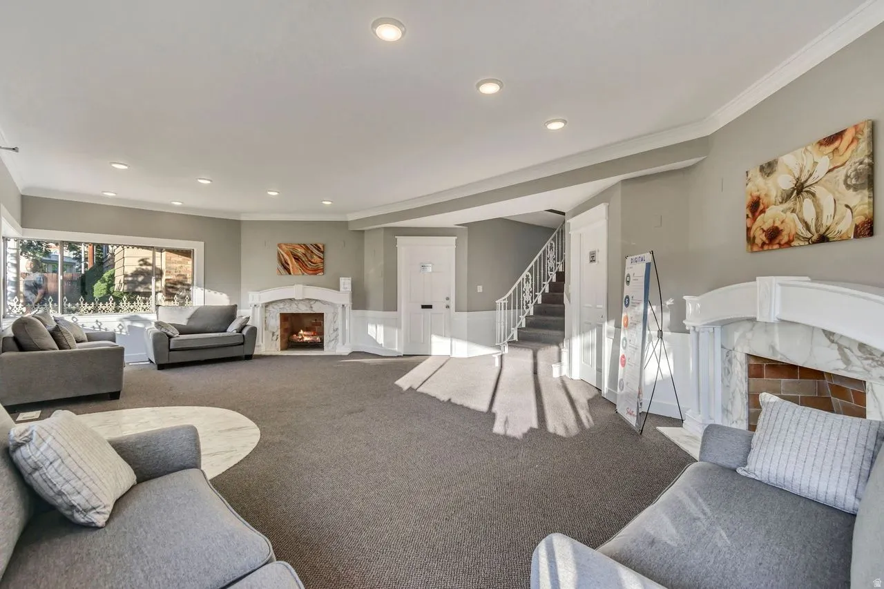 Spacious living area featuring two fireplaces with marble surrounds and detailed white mantels