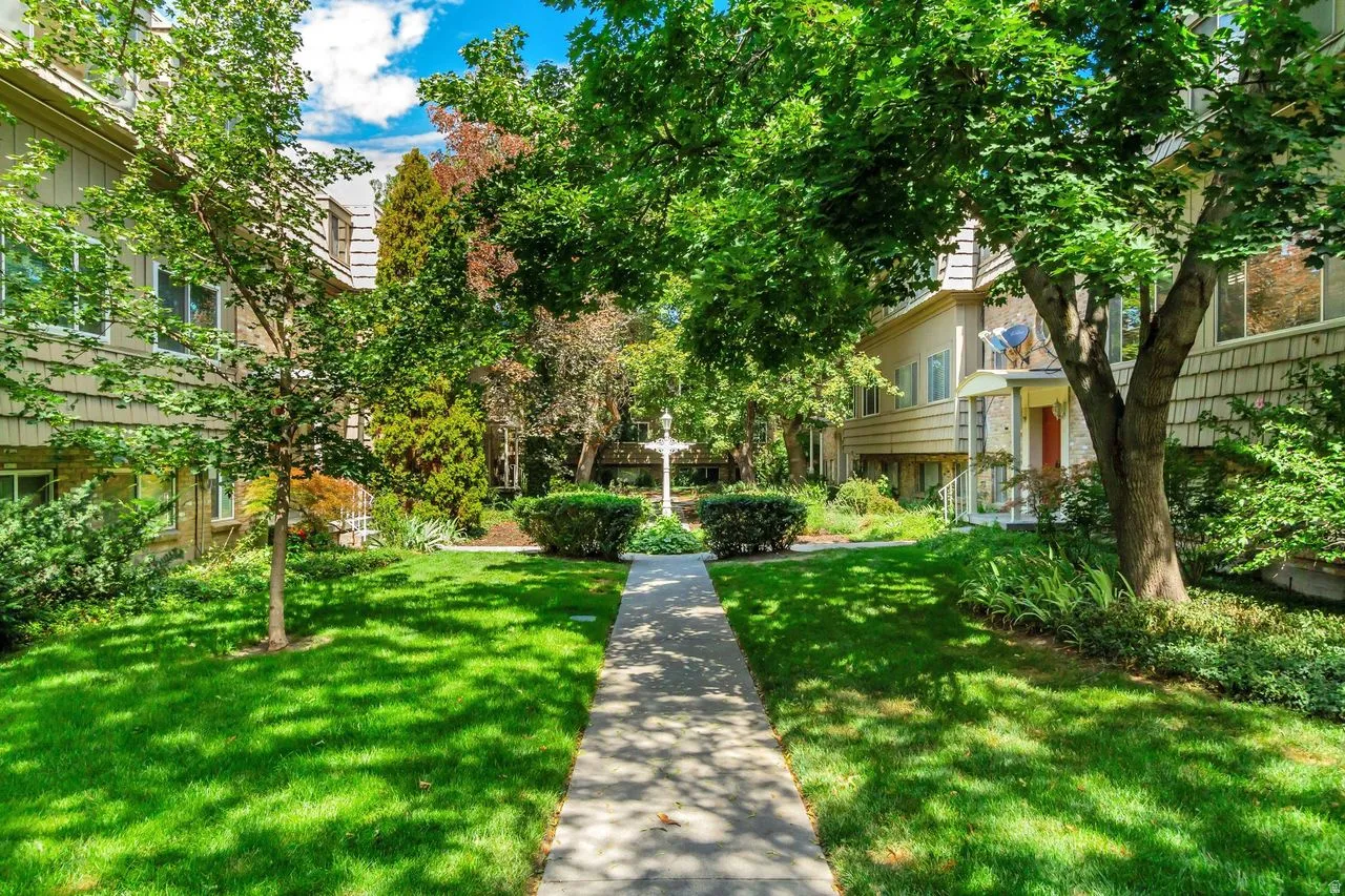 Serene courtyard showcasing a manicured lawn, mature trees providing natural shade, and established landscaping