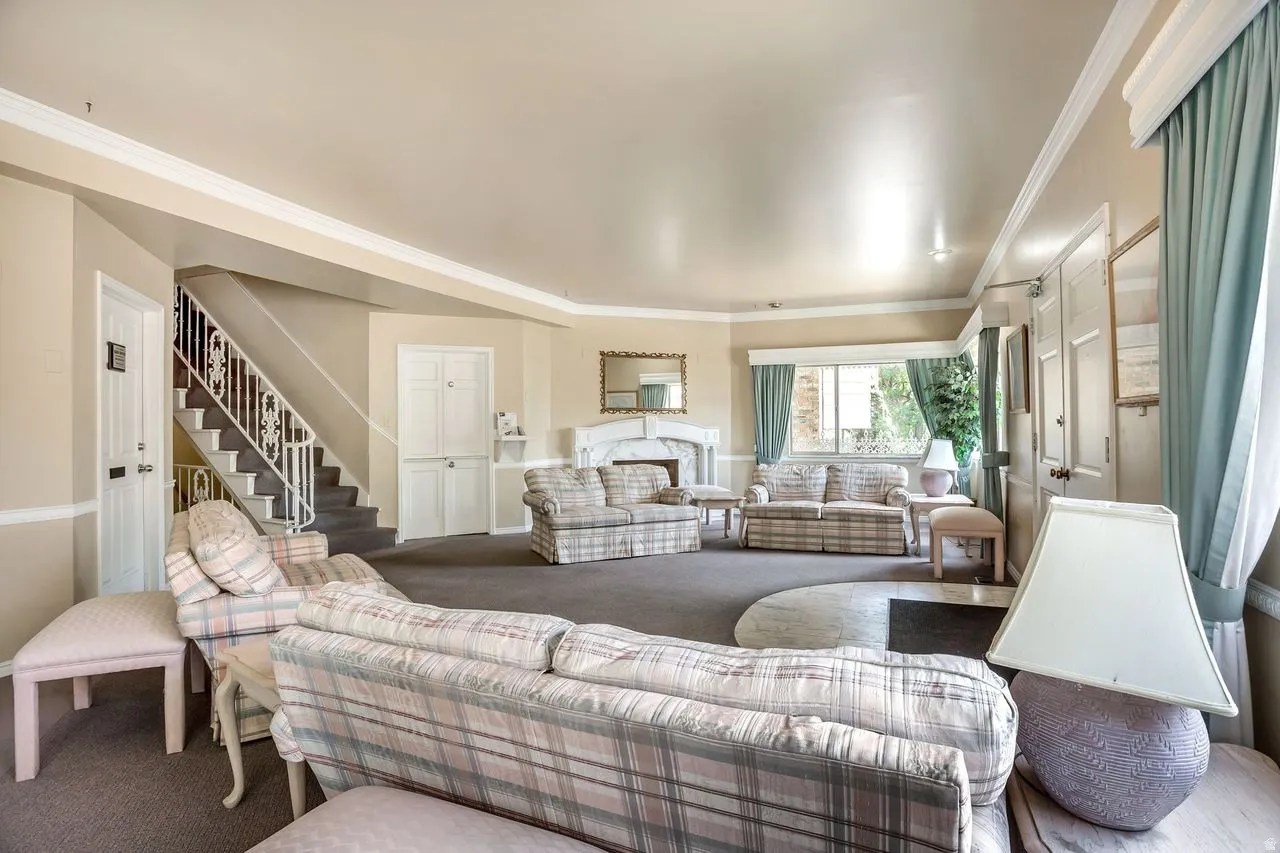 Sophisticated open-concept living area featuring soaring ceilings with recessed lighting, neutral plaid upholstered seating, wood-finish flooring throughout, large windows with sage green drapery, and a curved architectural layout