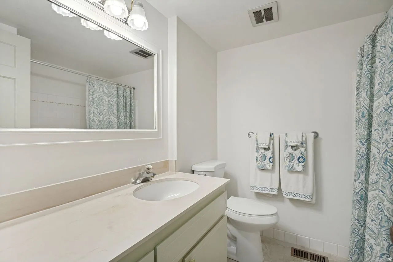 Bathroom featuring a vanity with an integrated sink, a light-toned countertop, and a white framed mirror with overhead lighting