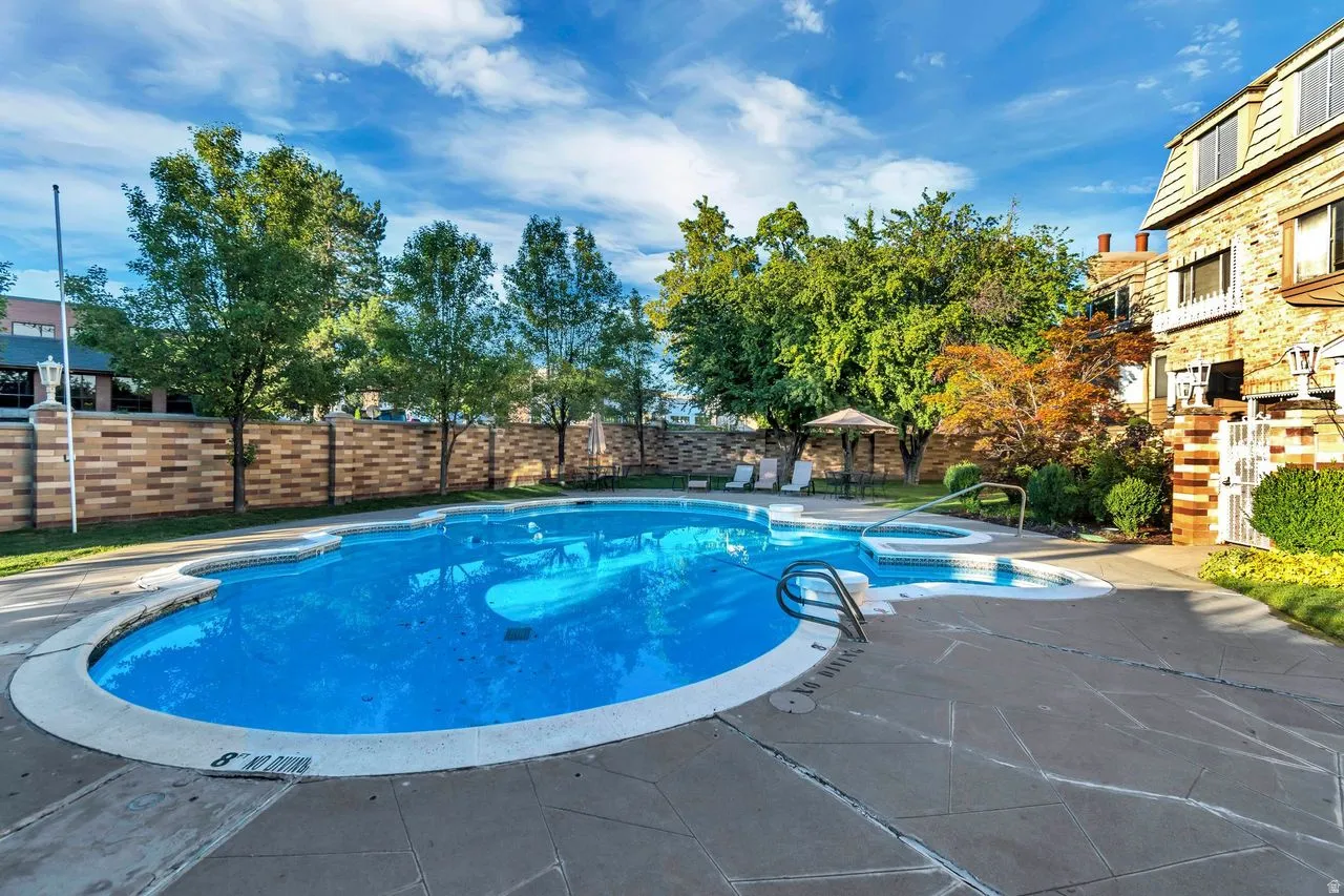 Freeform swimming pool with integrated hot tub, surrounded by flagstone-style paving