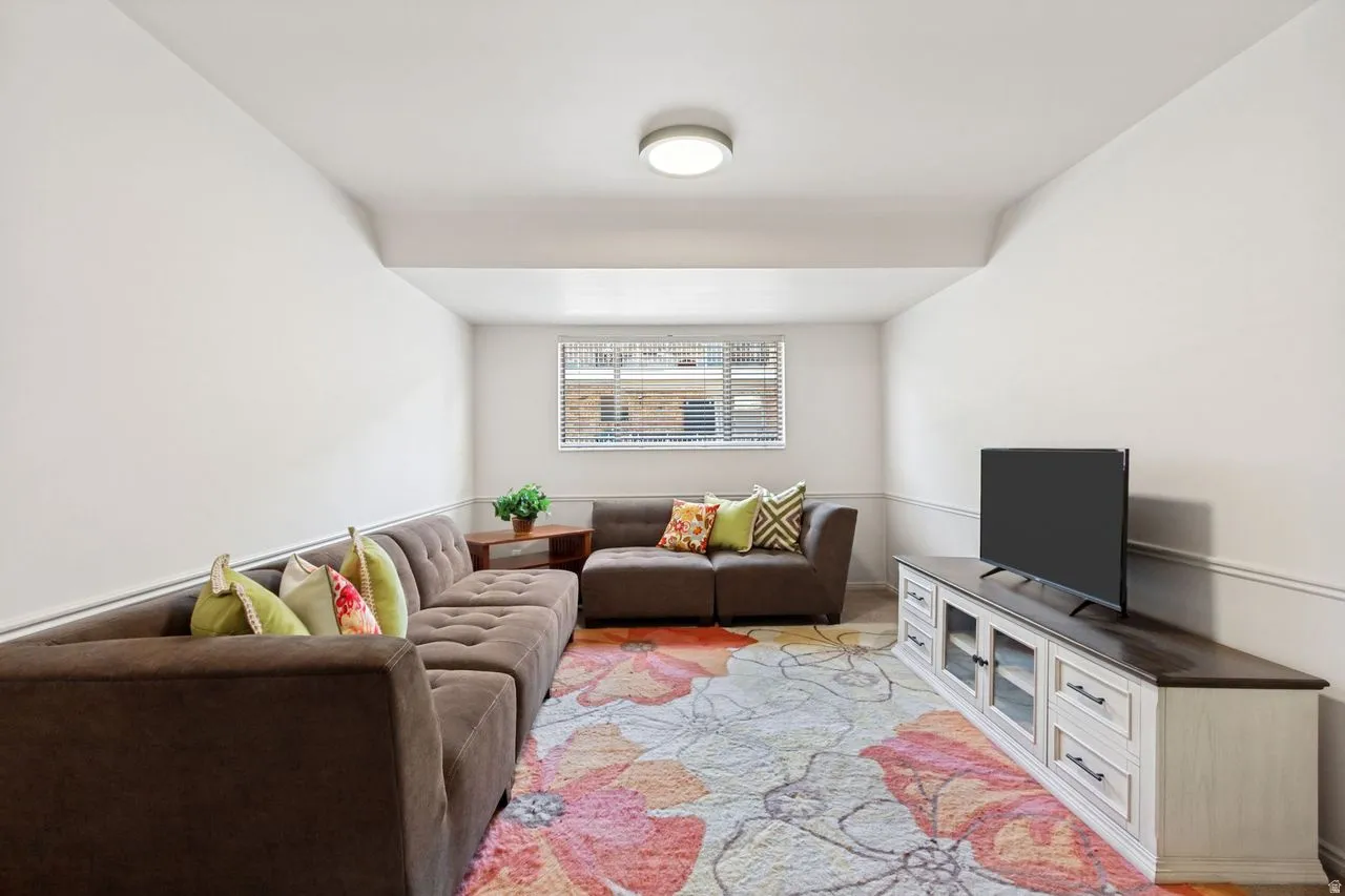 Recreation room featuring a window with blinds, overhead flush-mount lighting, and decorative wall molding