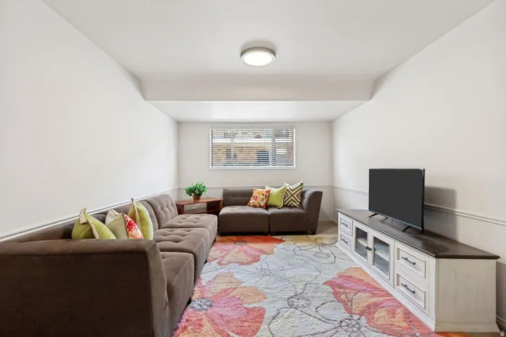 Recreation room featuring a window with blinds, overhead flush-mount lighting, and decorative wall molding
