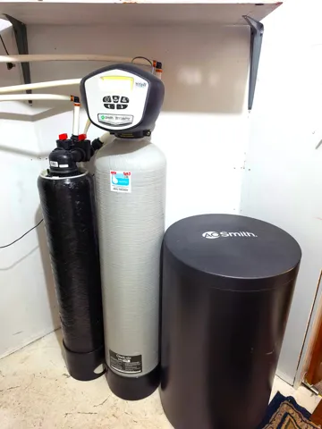 Integrated water treatment system featuring three vertical tanks and visible plumbing connections