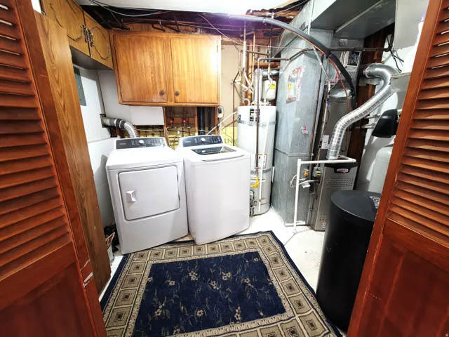Utility area featuring wood-finish cabinetry, a hot water heater, and a furnace