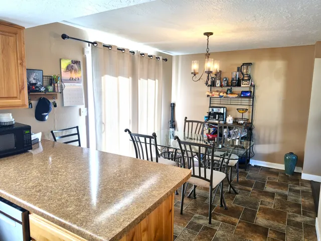 Kitchen and dining area featuring a breakfast bar with a speckled countertop, natural wood-finish cabinetry, and a glass sliding door