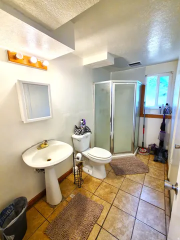 Pedestal sink with wall-mounted mirror and vanity lighting
