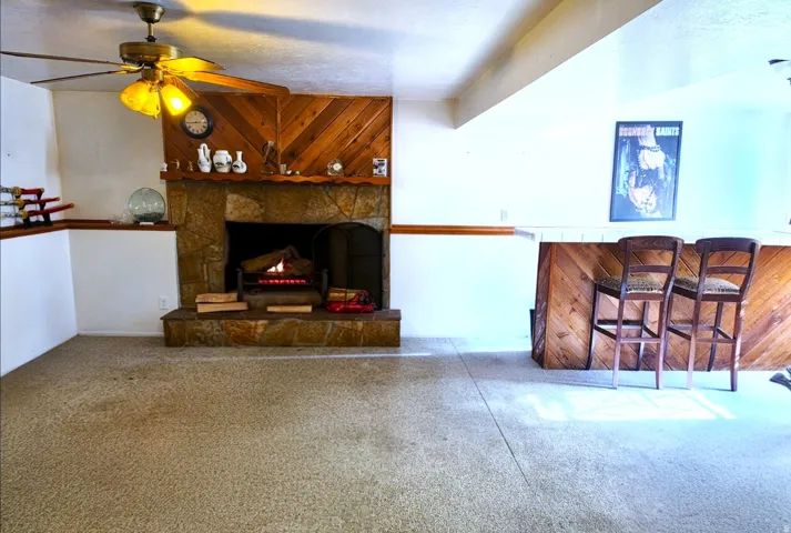Stone-faced fireplace with a wood-paneled accent wall, accompanied by a built-in bar featuring wood-paneling