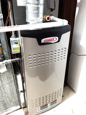 Lennox furnace unit featuring a metal exhaust pipe and various utility connections