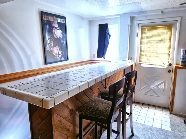 Custom built-in bar featuring a tiled countertop and wood-finish paneling