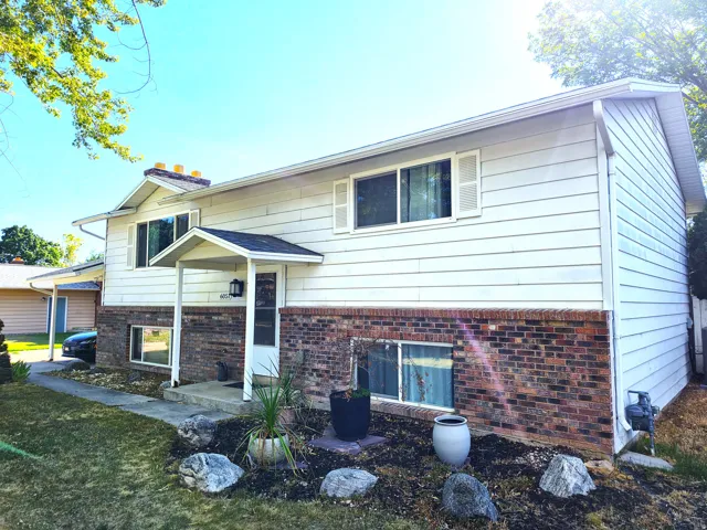 Split-level exterior featuring white siding and a brick facade