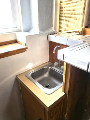 Compact stainless steel sink with a two-handle faucet, set into a laminate countertop