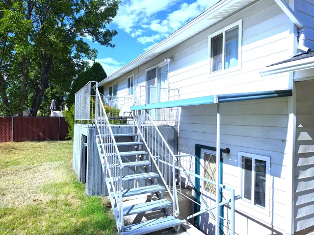 Exterior featuring vinyl siding, a second-story balcony with metal railings, and a ground-level door with security bars