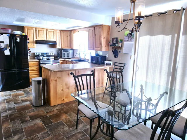 Kitchen and dining area featuring warm wood cabinetry, neutral countertops, and stainless steel appliances