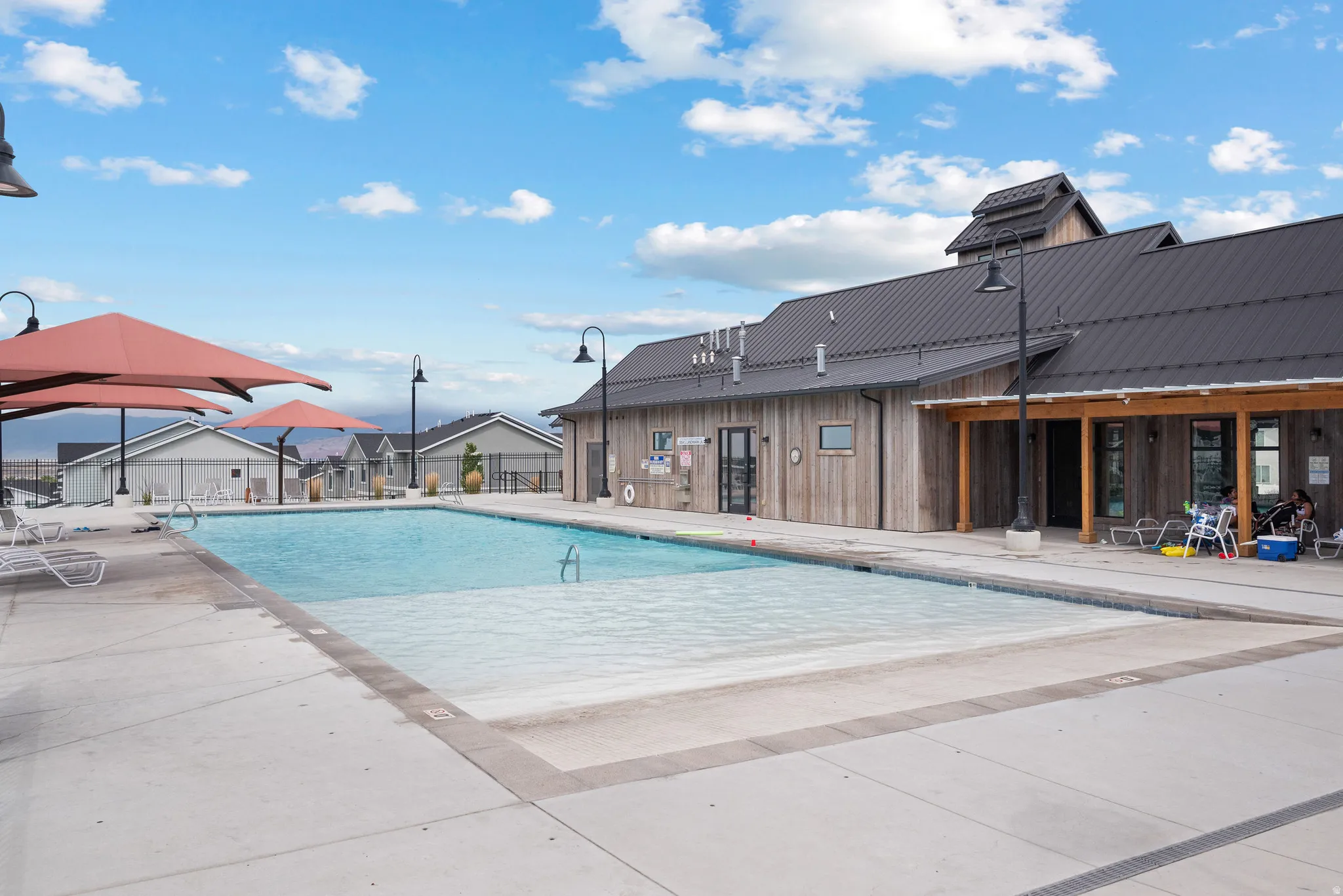Resort-style community swimming pool with crystal-clear waters and sun lounging area, complemented by a spacious concrete deck and covered poolside pavilion
