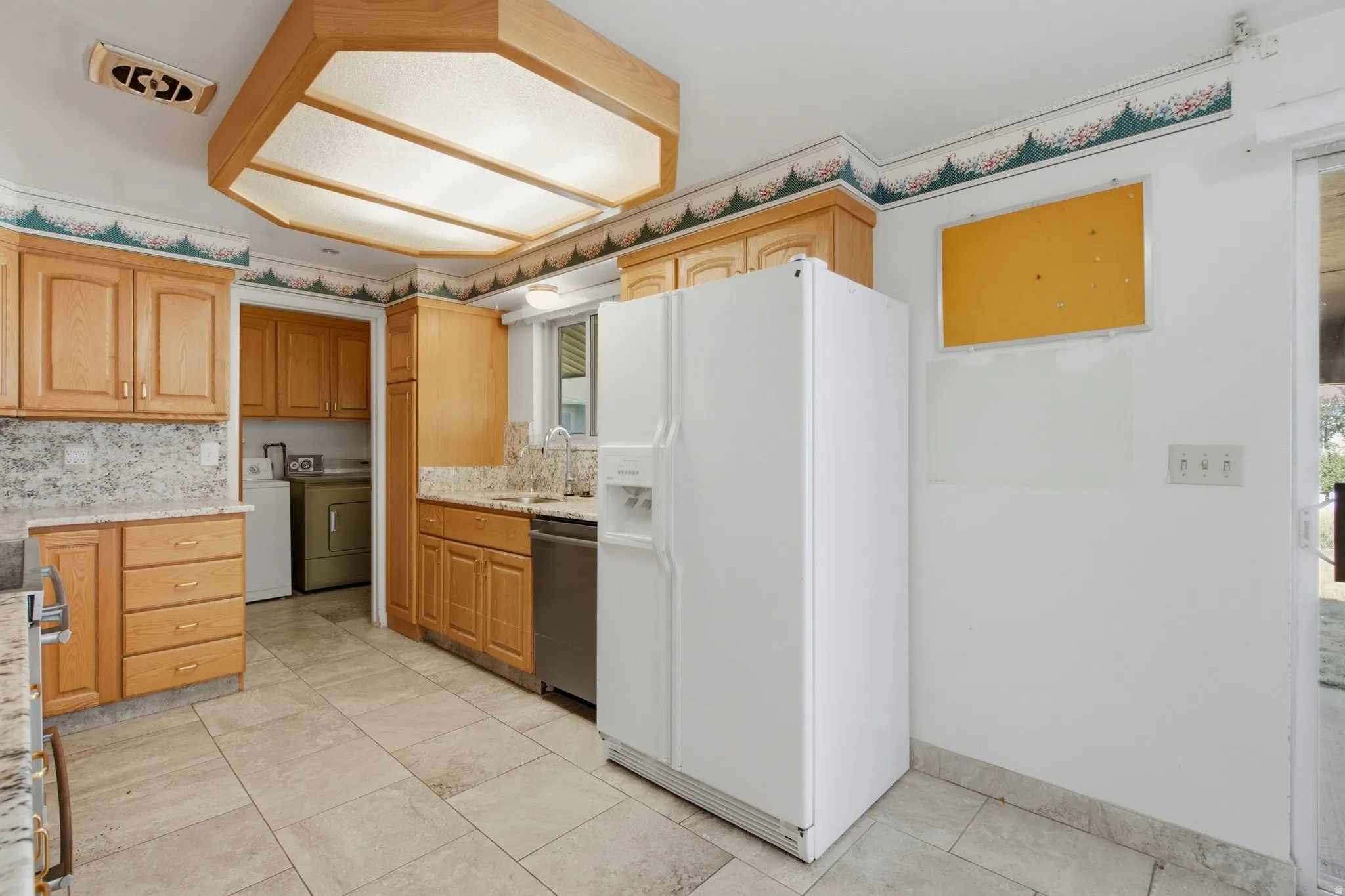 Kitchen featuring natural wood cabinetry, light-toned stone countertops, and tile flooring