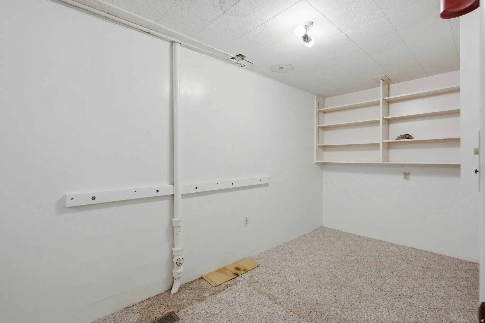Room featuring light-colored carpeting, built-in shelving, and a textured ceiling