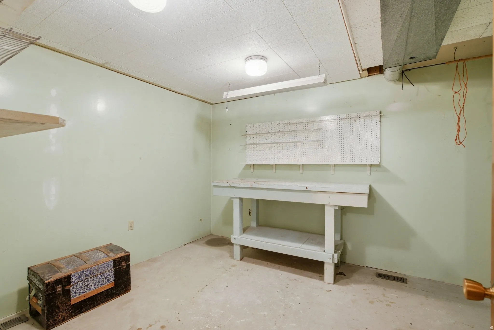 Utility room featuring a built-in workbench, wall-mounted pegboard, and overhead fluorescent lighting
