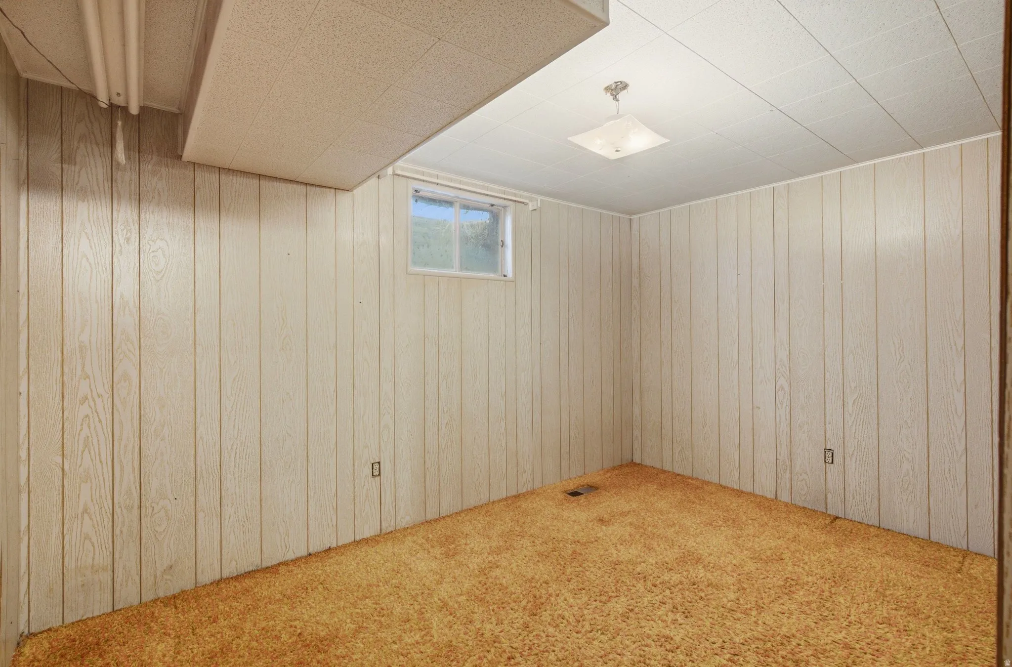 Room with light-toned vertical paneling, a textured ceiling, and a single window