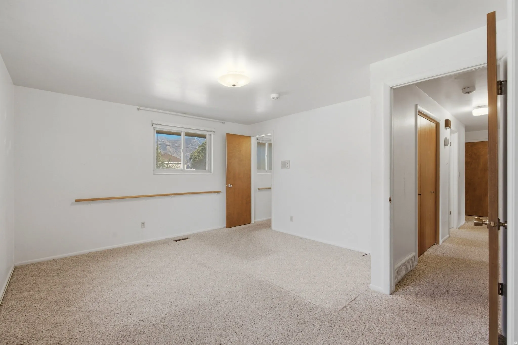 Carpeted room with white walls, a window, and wood doors