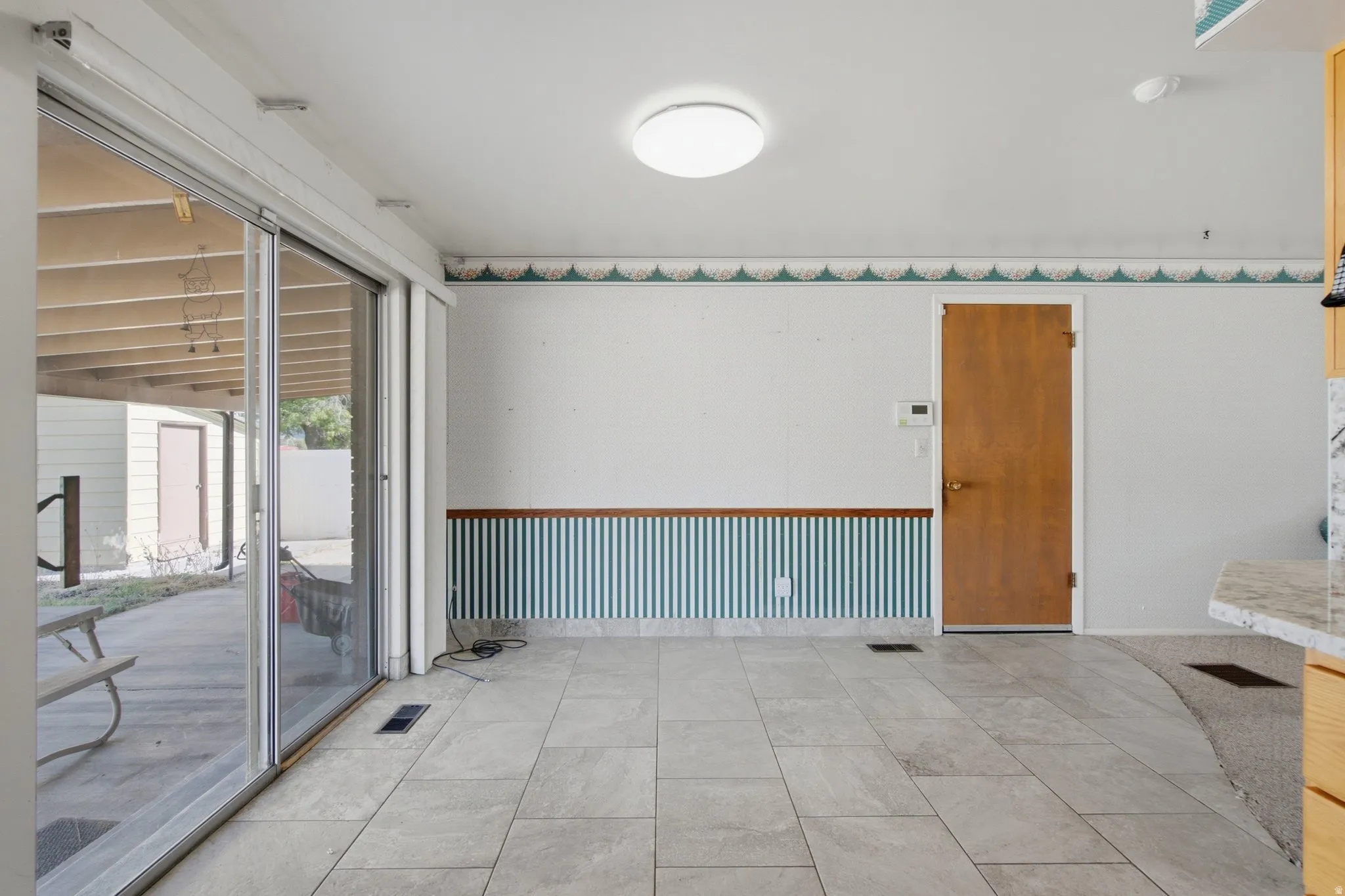 Spacious room featuring light-toned tile flooring and a full-light sliding glass door
