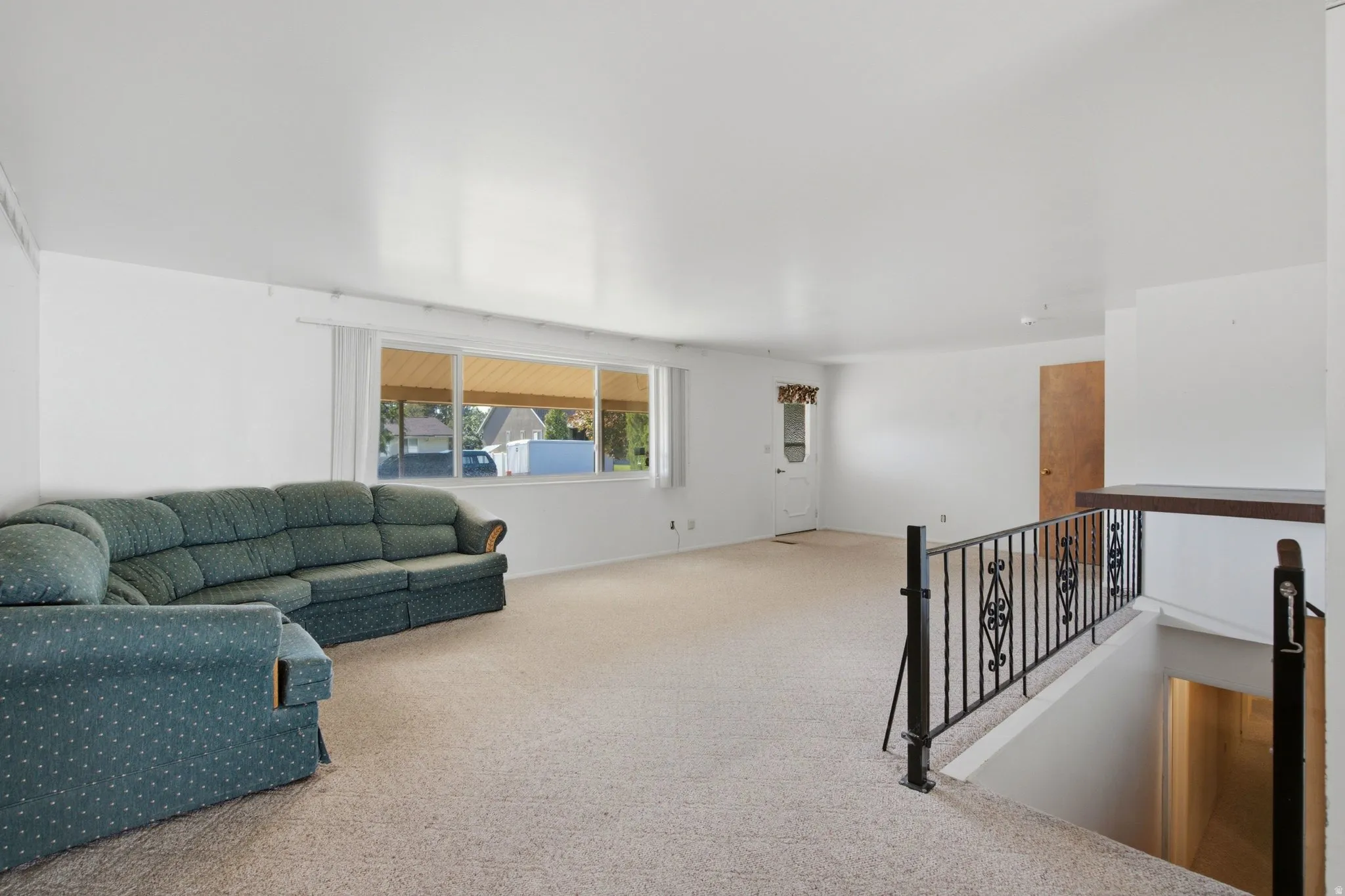 Expansive interior space featuring light-colored carpeting, white walls, and a large multi-pane window