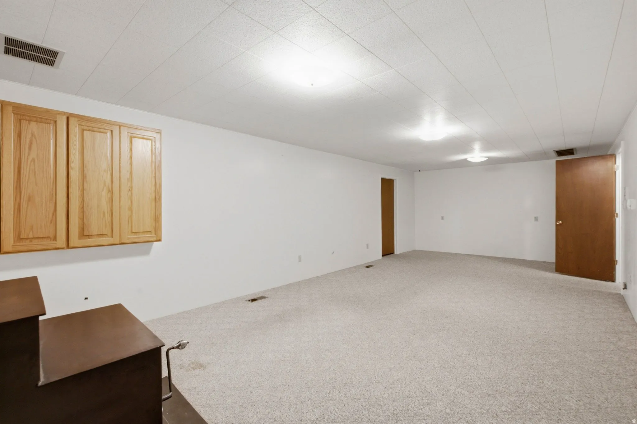 Spacious room featuring light-colored carpeting and crisp white walls