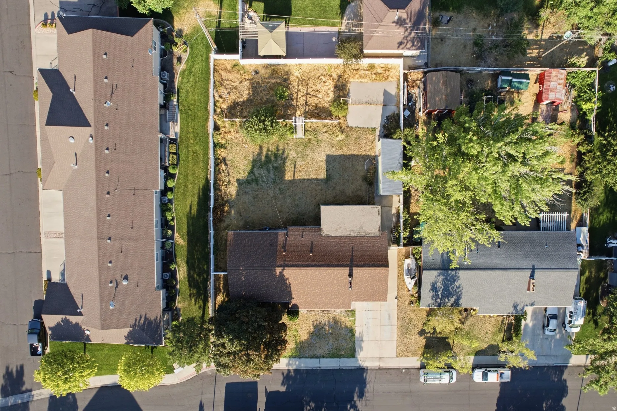 Aerial view showcasing a residential property with a dark shingle roof and a concrete driveway
