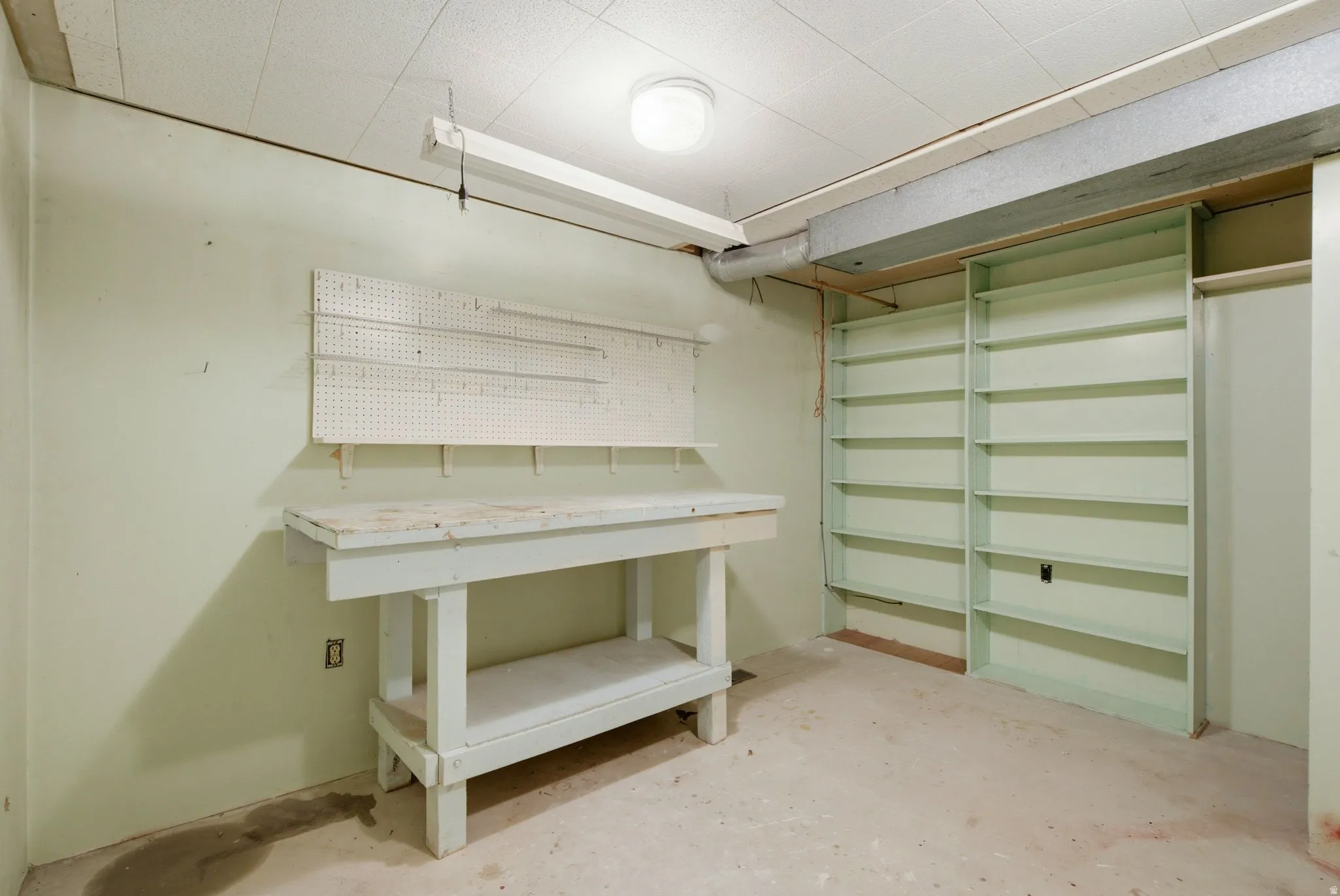 Utility room featuring a built-in workbench, pegboard storage, and extensive shelving