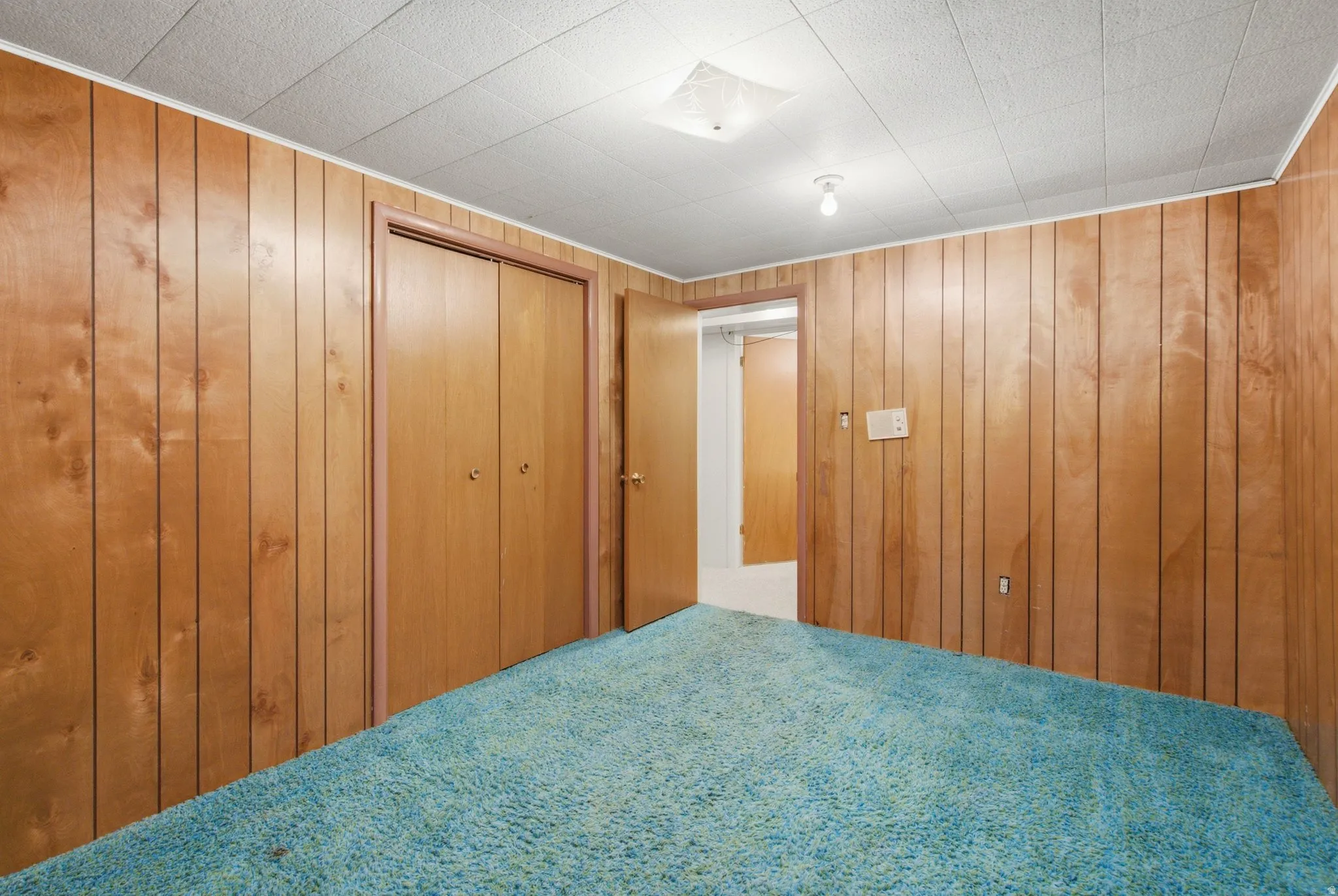 Paneled walls featuring a double-door closet and a secondary doorway