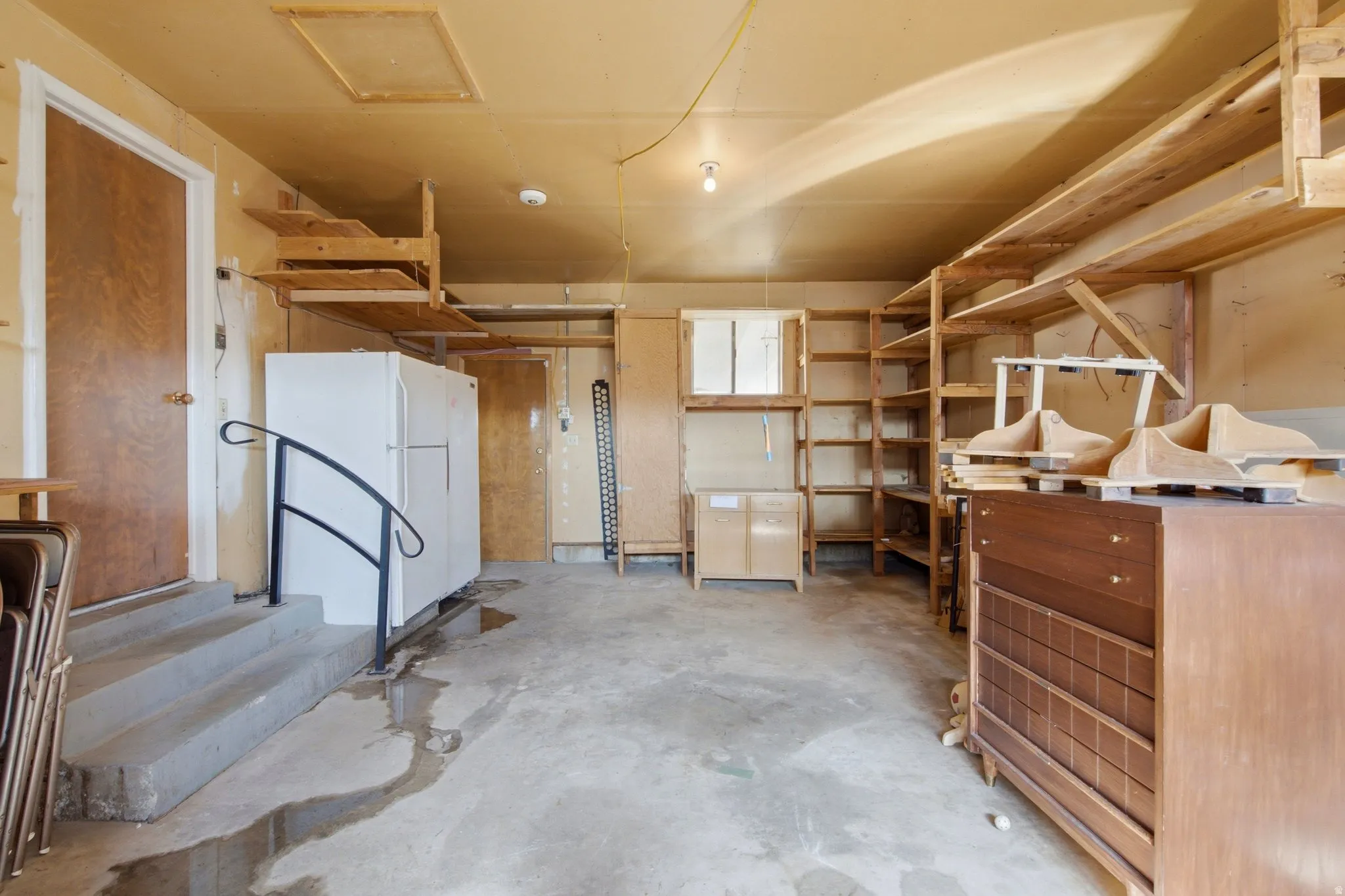 Spacious utility room featuring extensive wooden shelving and storage cabinetry, concrete flooring, and overhead recessed lighting