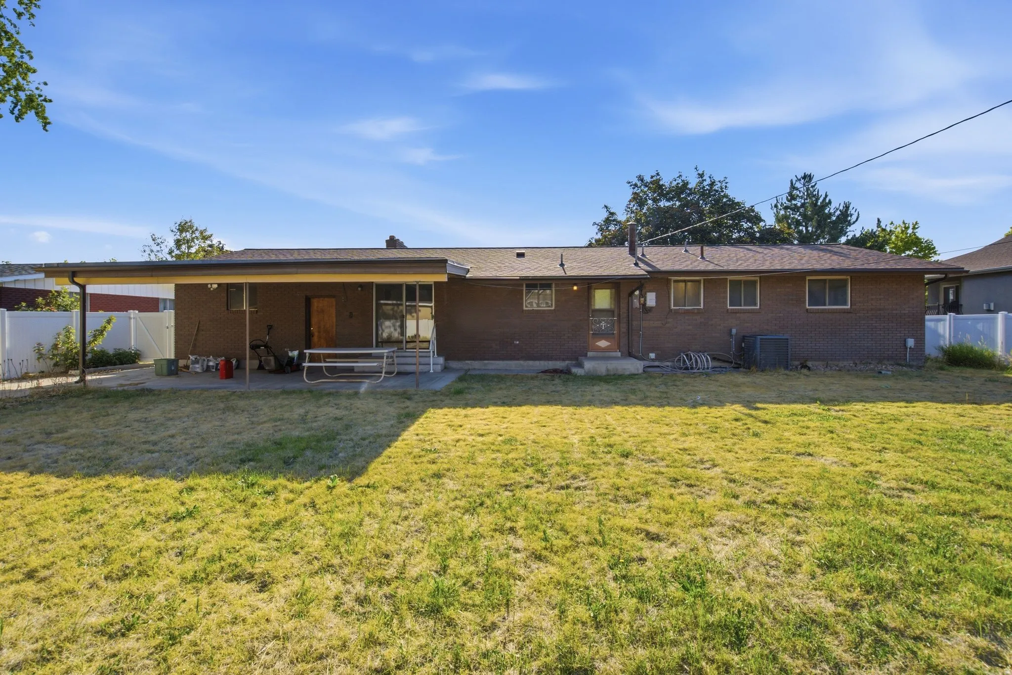 Expansive backyard featuring a covered patio, a full brick exterior, a multi-pane glass door, and multiple windows