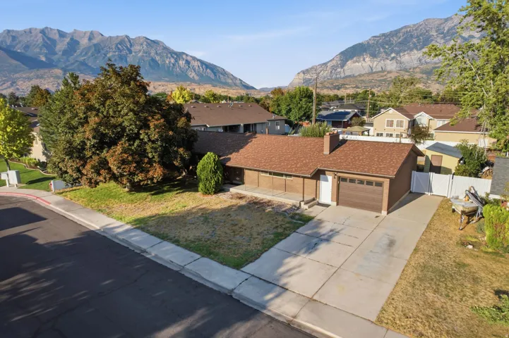 Single-story residence featuring a brown shingle roof, attached garage with a brown door, and a concrete driveway