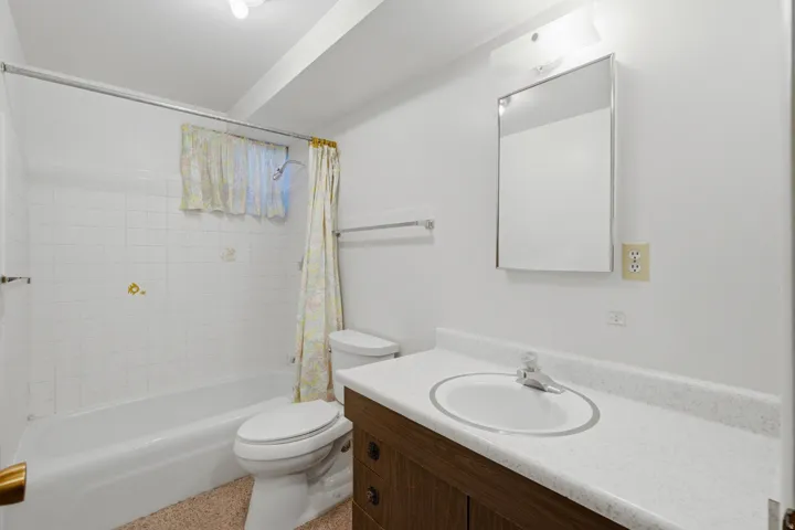 Clean and functional bathroom featuring a wood-finish vanity with dual drawers, white ceramic sink, and white quartz countertop
