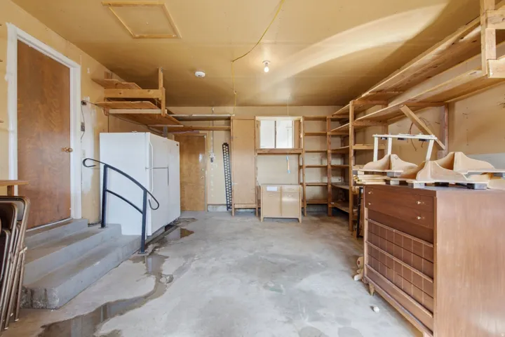 Spacious utility room featuring extensive wooden shelving and storage cabinetry, concrete flooring, and overhead recessed lighting